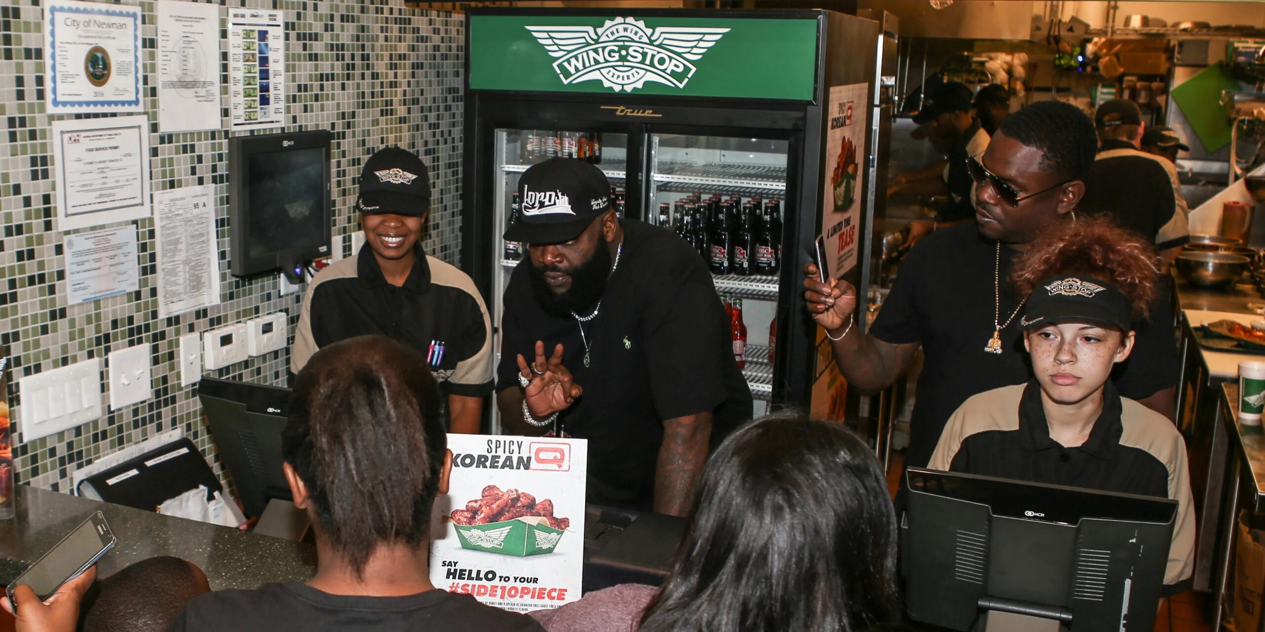 Rick Ross getting order from customers at a WingStop location